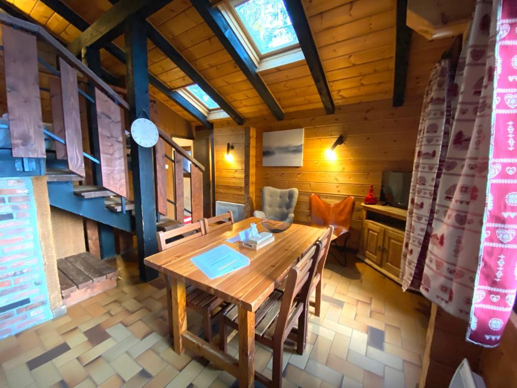 een eetkamer met een houten tafel en stoelen bij LE FLOCON 1 Appartement avec terrasse in La Bresse