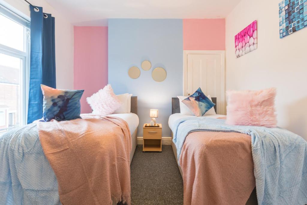 two beds in a room with pink and blue at Lovely 2 Bedroom 3 Beds SOJ In Great Location Hull in Hull