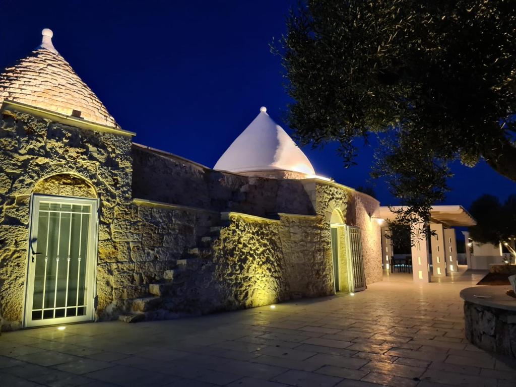 - un bâtiment en pierre avec un portail la nuit dans l'établissement I trulli di Uma, à Carovigno
