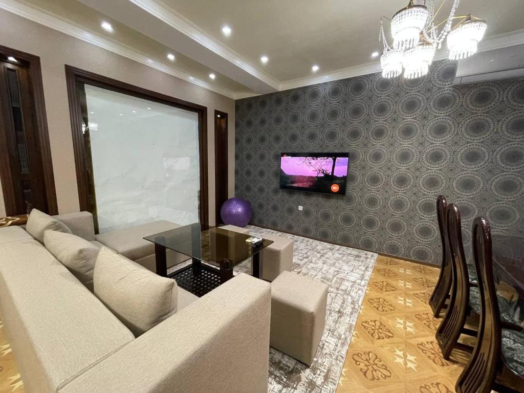 a living room with a couch and a tv on a wall at Comfortable apartments complex at Nova Garden near Disney Land in Tashkent