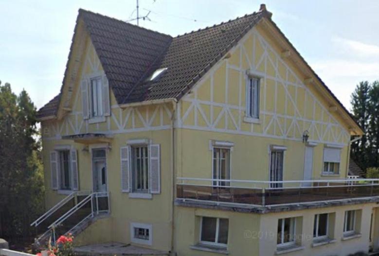 duży żółty dom z czarnym dachem w obiekcie Gîte de l’Allaine w mieście Morvillars