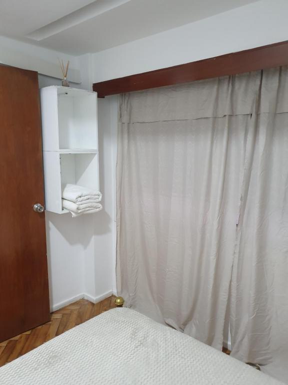 a bedroom with a bed and a white curtain at Obelisco Deptos in Buenos Aires