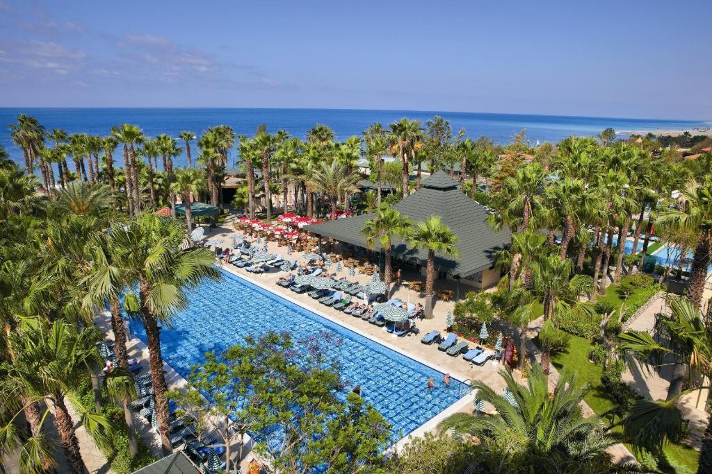 an aerial view of a resort pool with palm trees and the ocean at Meryan Hotel - Ultra All Inclusive in Okurcalar