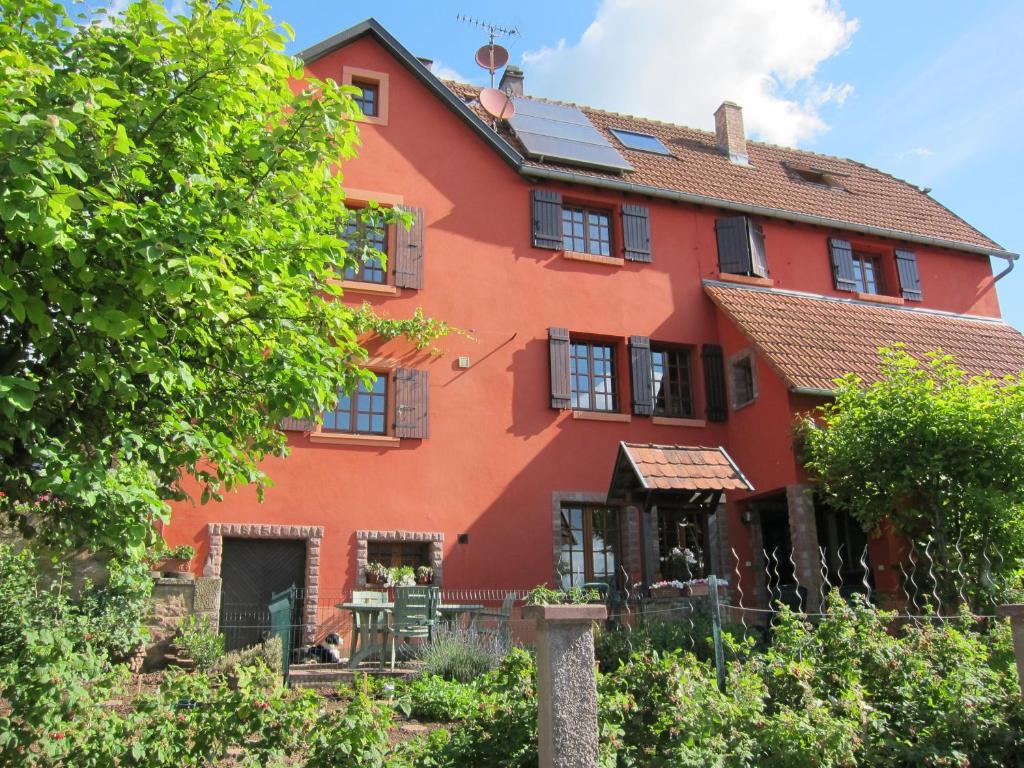 una casa naranja con un árbol delante de ella en Gîte la Ferme, en Mutzig