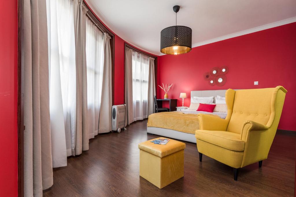 ポルトにあるOporto Santa Catarina Residenceの赤い壁のベッドルーム1室、黄色いベッド1台、椅子が備わります。
