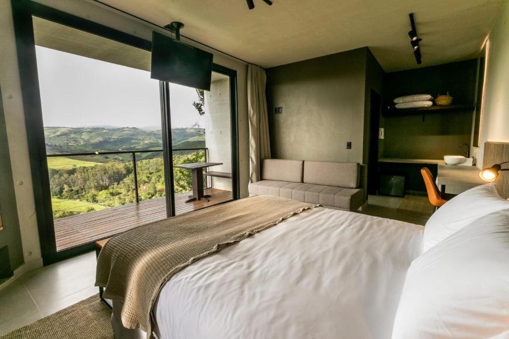 a bedroom with a large bed and a large window at Pousada Casa Bambu in Cunha