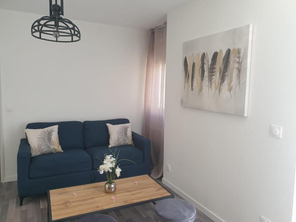 sala de estar con sofá azul y mesa en Le bel'air appartement chaleureux et calme oyonnax, en Oyonnax
