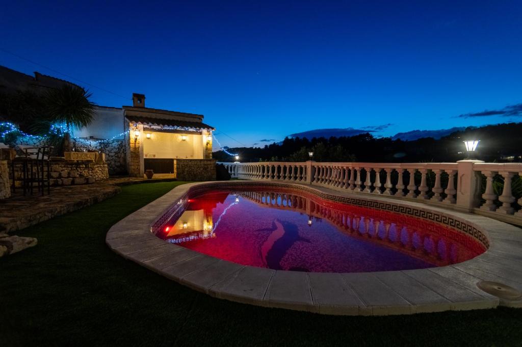 a pool with red lights in a yard at night at Casa au Lilas Rosa in Benissa