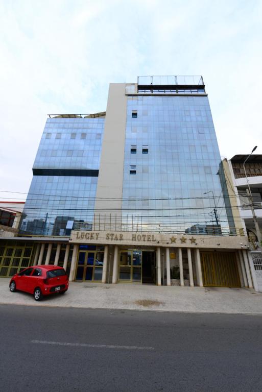 un coche rojo estacionado frente a un edificio en Hotel Lucky Star, en Chiclayo