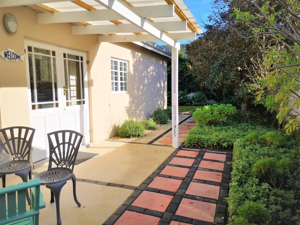 赫曼努斯Seashell Cottage的一个带椅子的庭院和一个白色凉亭