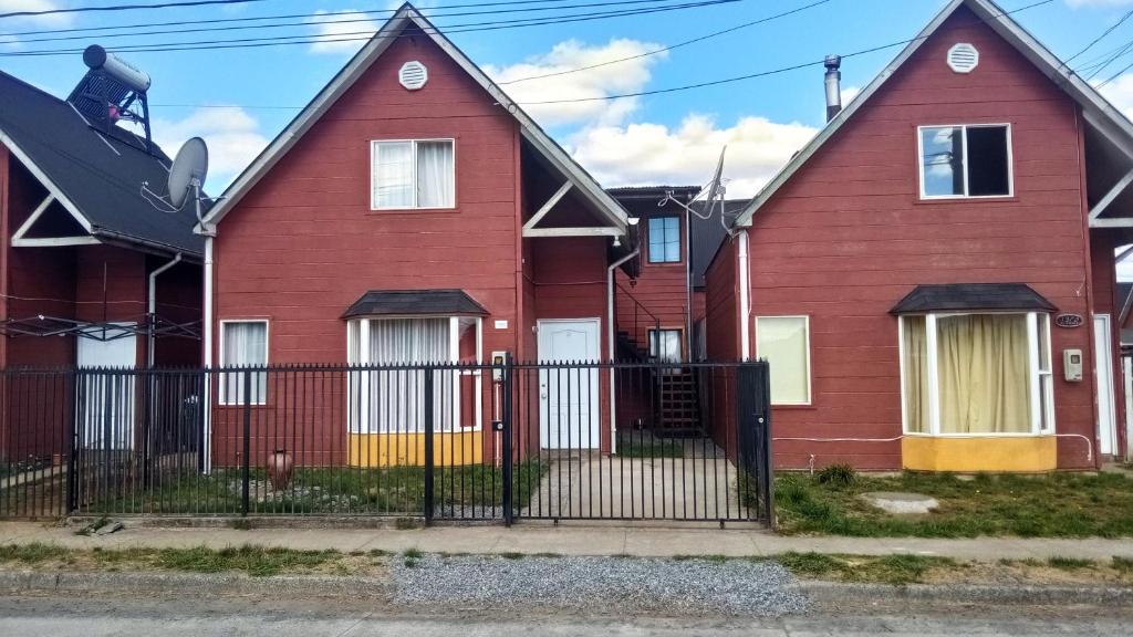 una fila de casas rojas con una valla negra en Casa Parque Villarrica, Los Albatros, en Villarrica