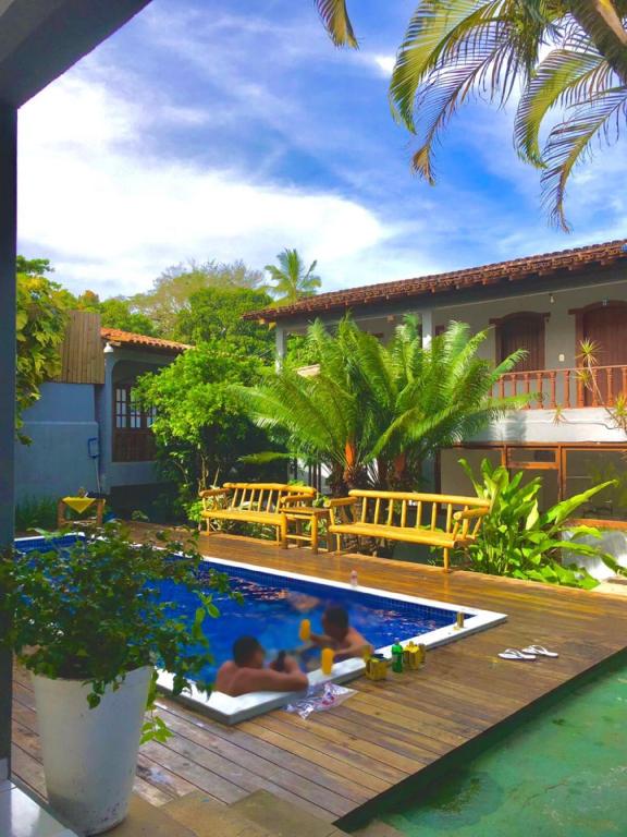 two people laying in a swimming pool next to a house at DORM Olhar da Sereia in Arraial d'Ajuda