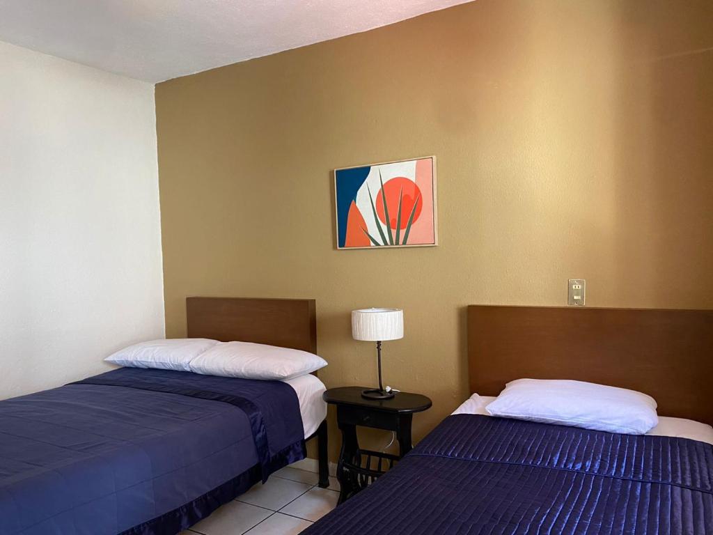 Habitación con 2 camas y mesa con lámpara. en Hotel Caracoles Colima, en Colima