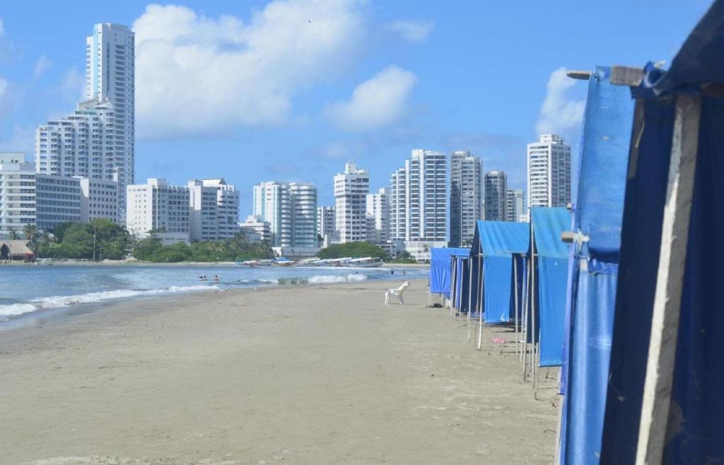 a row of blue beach umbrellas on a beach at 1IF2-2APARTAMENTO EN CARTAGENA CERCA AL MAR CON AIRE ACONDICIONADO Y WIFi in Cartagena de Indias