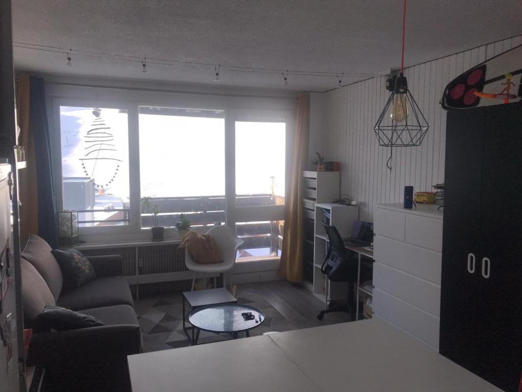 een woonkamer met een bank en een raam bij Mon studio pour 4 à Val Claret ! in Tignes