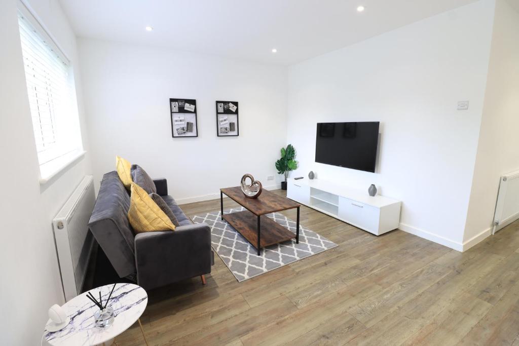 uma sala de estar com um sofá e uma televisão em Detached Bungalow - Sleeps 8 - Free Parking, Fast Wifi, Smart TV and Garden by Yoko Property em Northampton