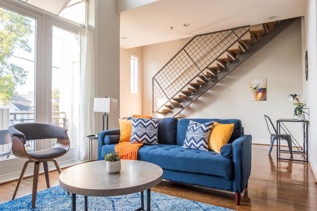 a blue couch in a living room with a staircase at FRONTDESK NuLu Apts Louisville in Louisville
