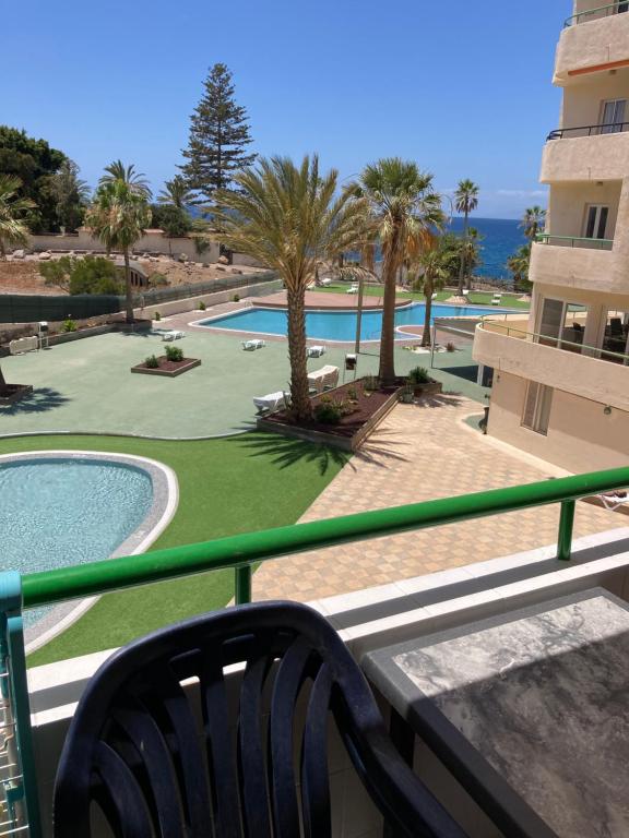 balcón con banco y piscina en Apartamentos Costamar en Arona