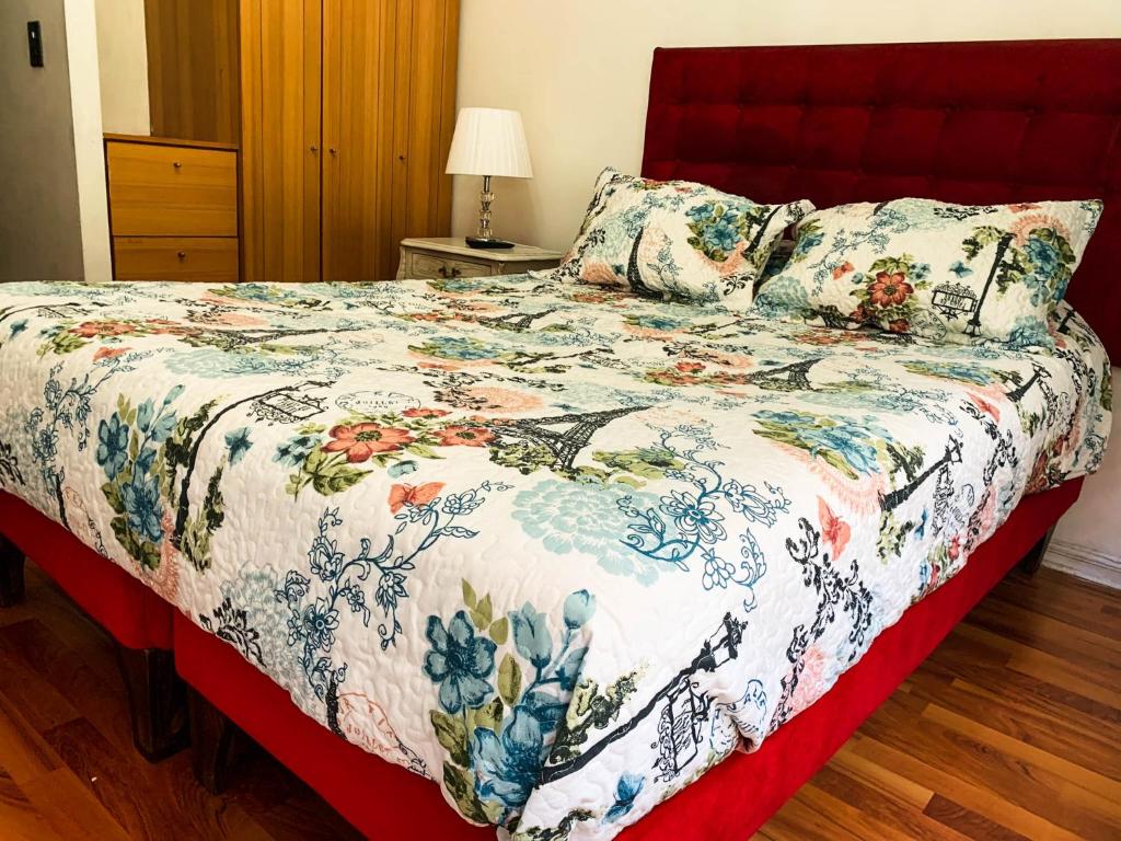 1 dormitorio con 1 cama con colcha de flores en Depto Metro Santa Ana, en Santiago