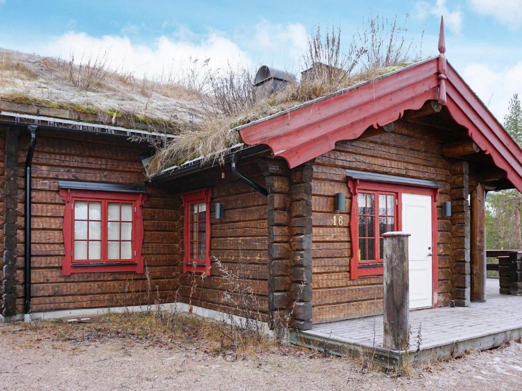 uma cabana de madeira com janelas vermelhas e um telhado de relva em 11 person holiday home in S LEN em Stöten