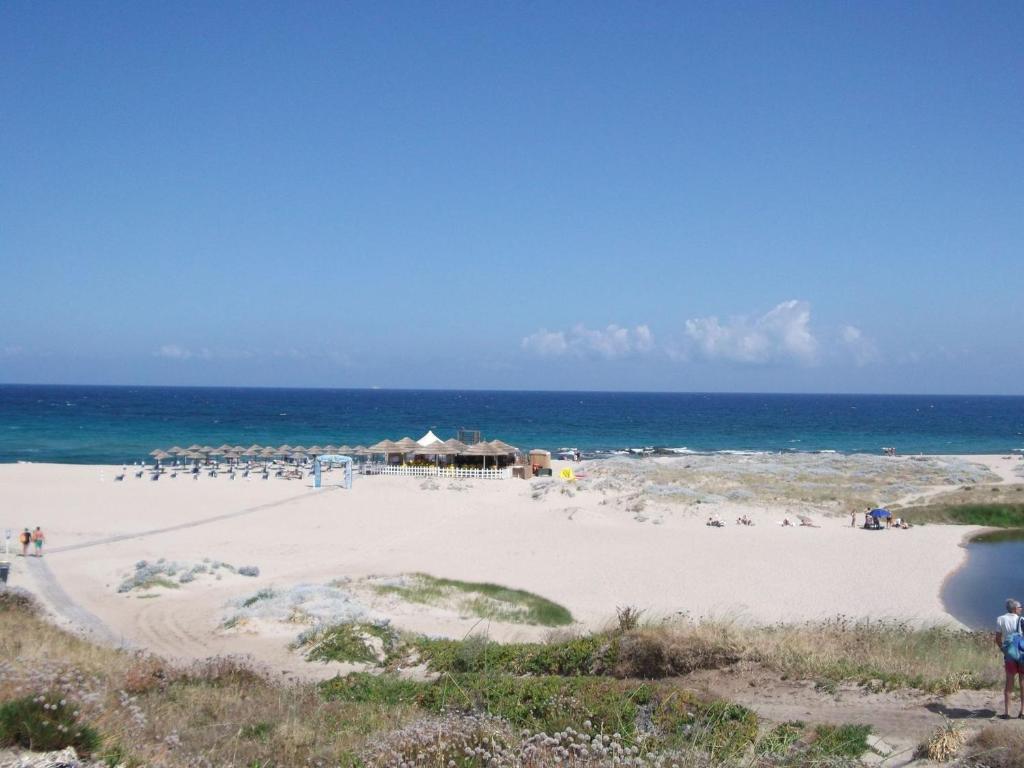 einen Strand mit einer Gruppe von Menschen auf dem Sand in der Unterkunft Appartamenti magnolie-La pineta in Valledoria