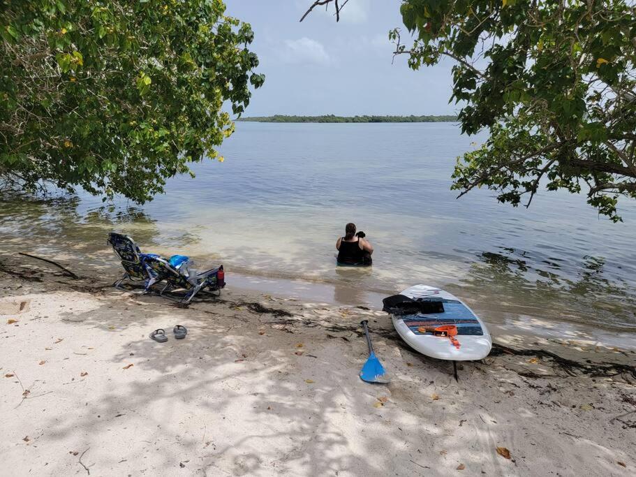 Una donna in piedi nell'acqua, accanto a una barca in acqua. di Private Beachfront House a Cabo Rojo