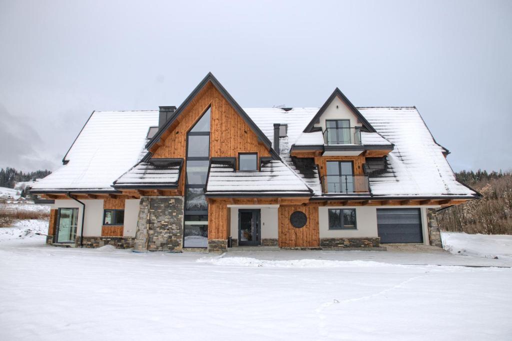 uma casa com neve no telhado em Hill House Apartamenty em Białka Tatrzanska