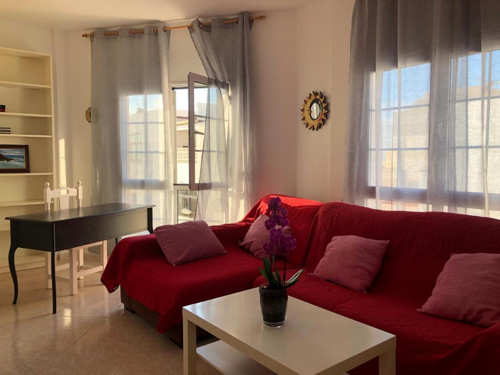 a living room with a red couch and a table at Apartamento vistas al mar, wifi de 600 Mb in Gran Tarajal