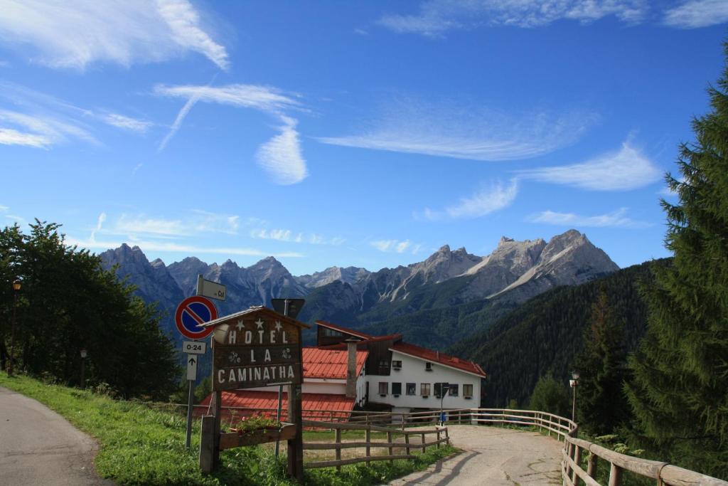 um sinal em frente a um edifício com montanhas ao fundo em Hotel La Caminatha em Val di Zoldo