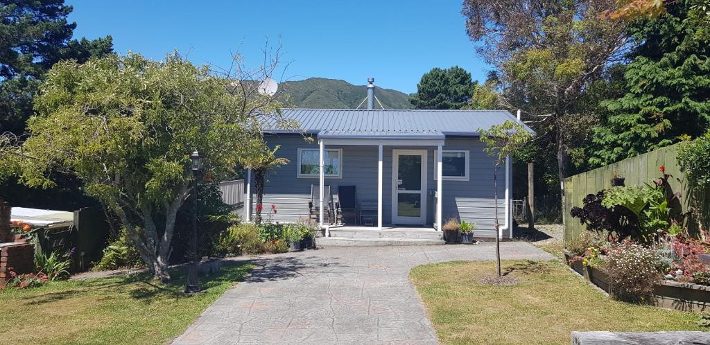 a blue house with a pathway leading to the front door at Incline Cottage in Upper Hutt