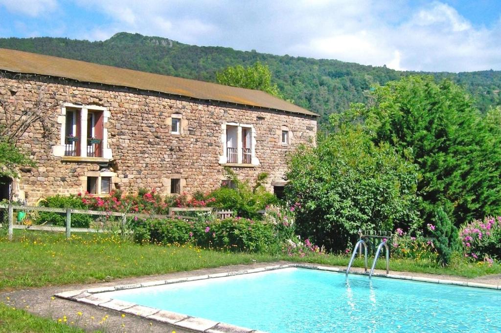 a swimming pool in front of a brick building at Holiday flat, Retournac in Retournac