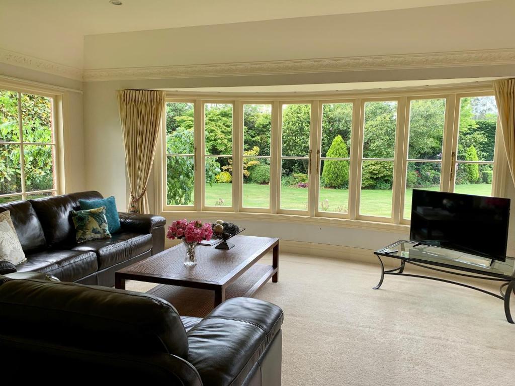 ein Wohnzimmer mit einem Sofa, einem TV und einem Tisch in der Unterkunft Pin Oaks Luxury Bed & Breakfast in Palmerston North