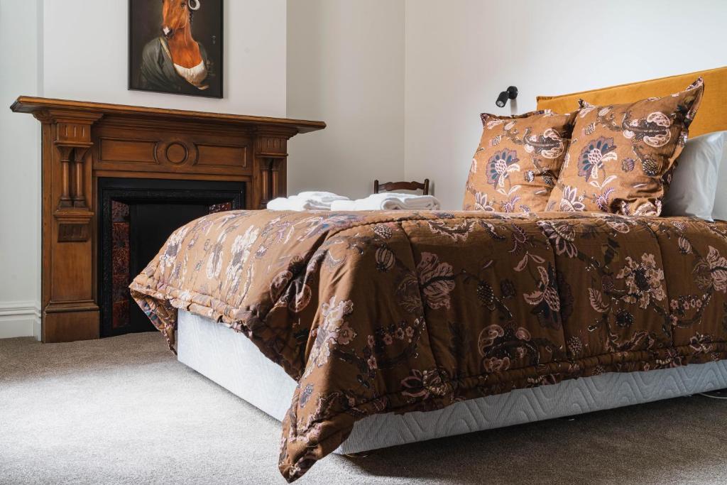 un letto con piumone marrone e camino di Premium Living on Stuart St a Dunedin