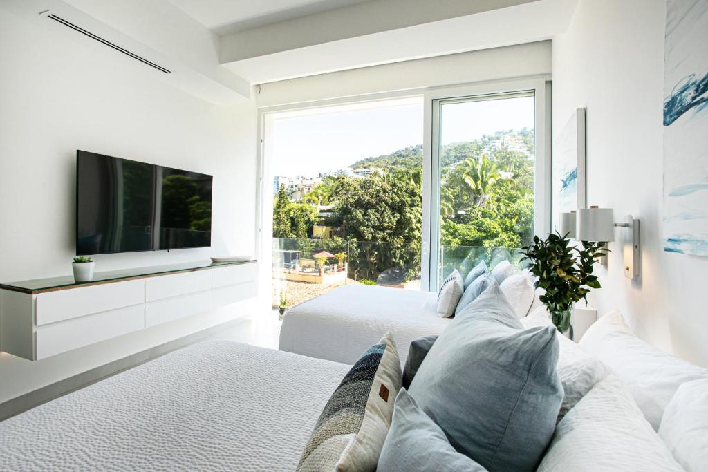 a white room with two beds and a tv at Casa Elevar at Orchid in Puerto Vallarta