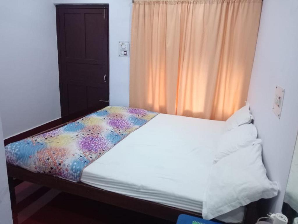a bed in a room with a window and a bedvisor at Coconhuts Beach Resort in Neil Island