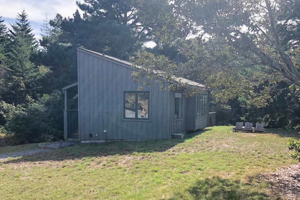 une petite maison grise dans une cour arborée dans l'établissement Madrone Cottage, à Sea Ranch