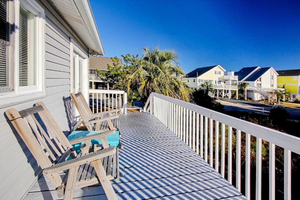 two wooden chairs sitting on the porch of a house at Holden onto Sunshine in Holden Beach