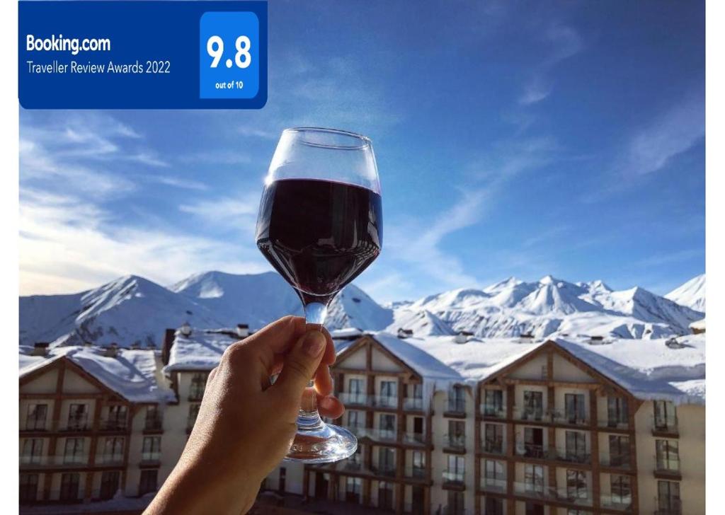 une personne tenant un verre de vin devant une montagne dans l'établissement New Gudauri Loft 2 #557, à Goudaouri