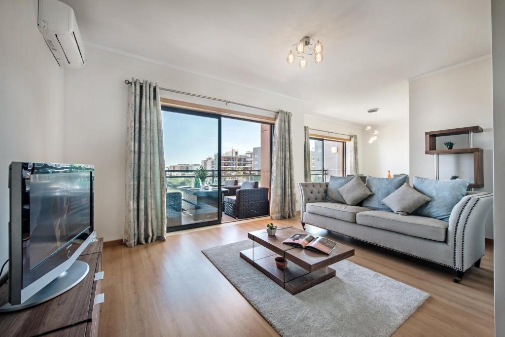 un soggiorno con divano e TV di Sunset Home Olhão- Modern 3 bed Luxury Apartment with rooftop pool a Olhão