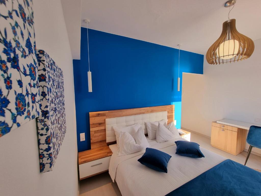 a bedroom with a blue wall and a bed with blue pillows at Hotel Nefeli in Volos