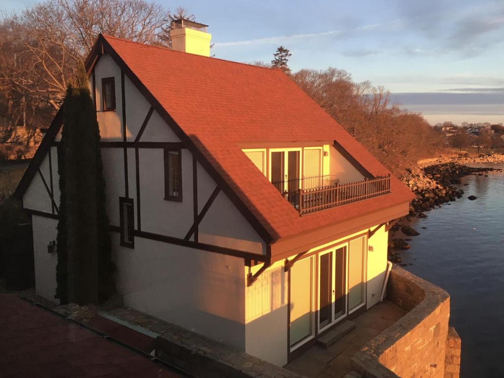 una casa con techo rojo sobre un cuerpo de agua en Point Radio Cottage, en Gloucester