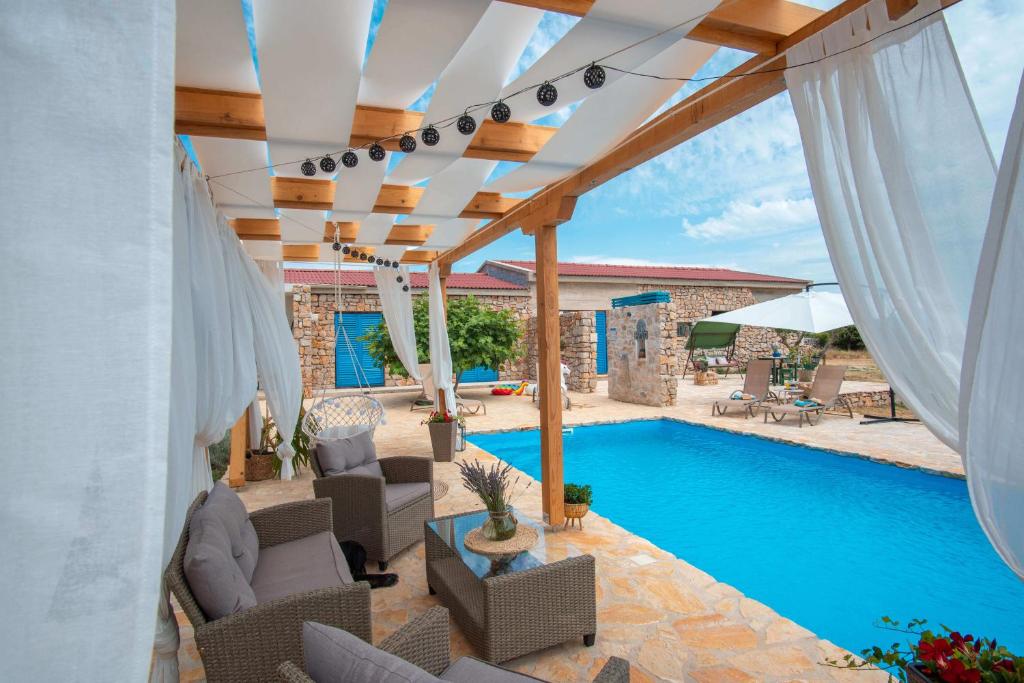 an outdoor patio with a swimming pool and a pergola at Opg Pelejš in Pag