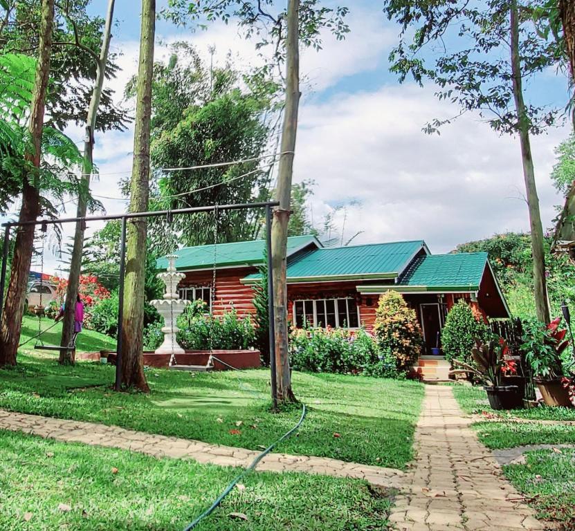 a house with a green roof and a hose at Dahilayan Comfy Cabin in Manolo Fortich