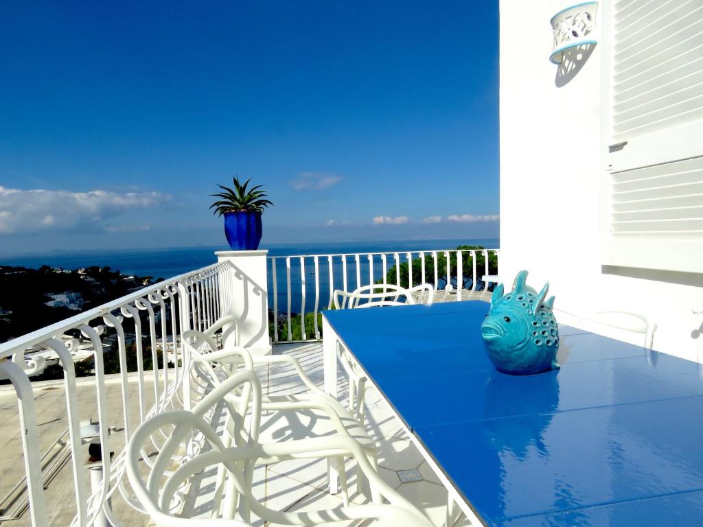 un tavolo blu e sedie su un balcone con vista sull'oceano di Blu Acquaviva a Capri