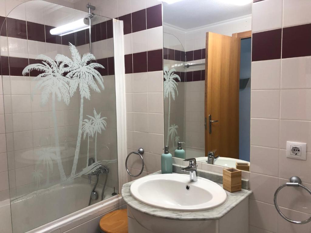 a bathroom with a sink and a tub and a mirror at Ericeira Surf and Sun in Ericeira