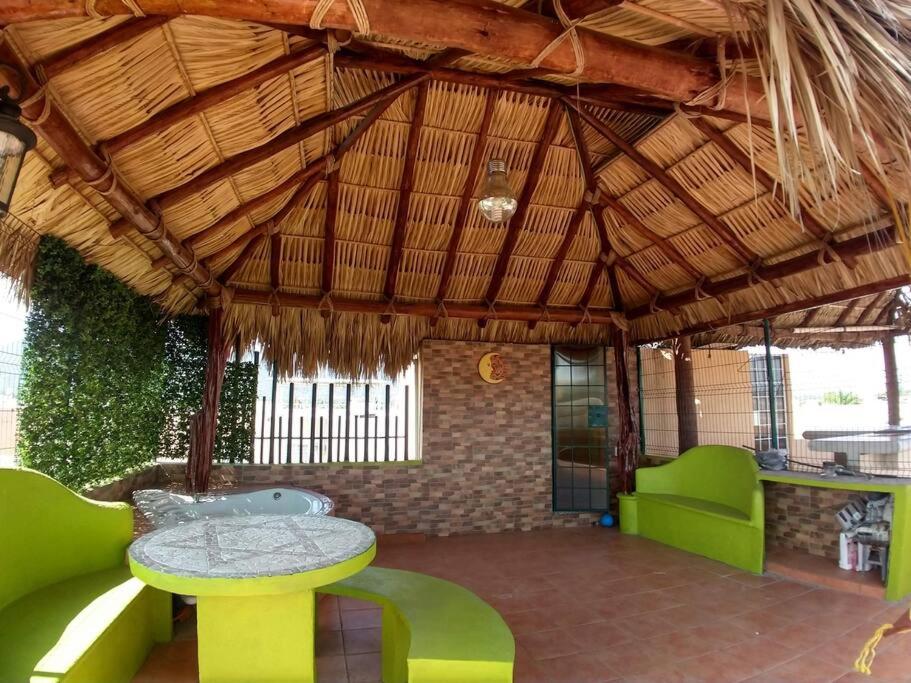 a patio with a table and green chairs in a pavilion at Casa Reliance: equipada, palapa privada y alberca in La Sabana