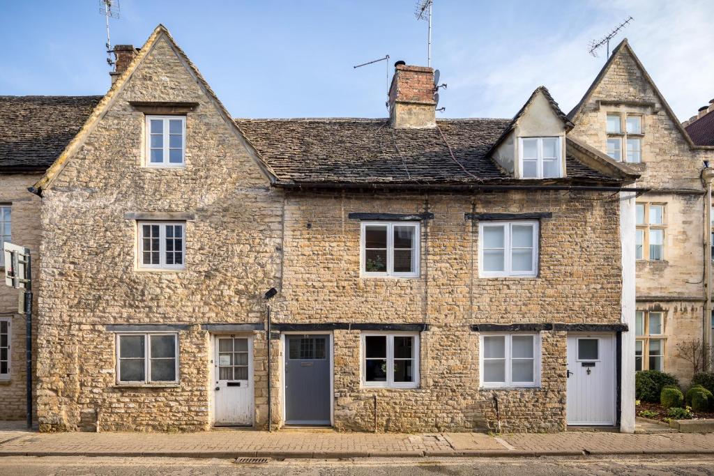 een oud stenen huis met witte deuren en ramen bij The Cottage in Cirencester