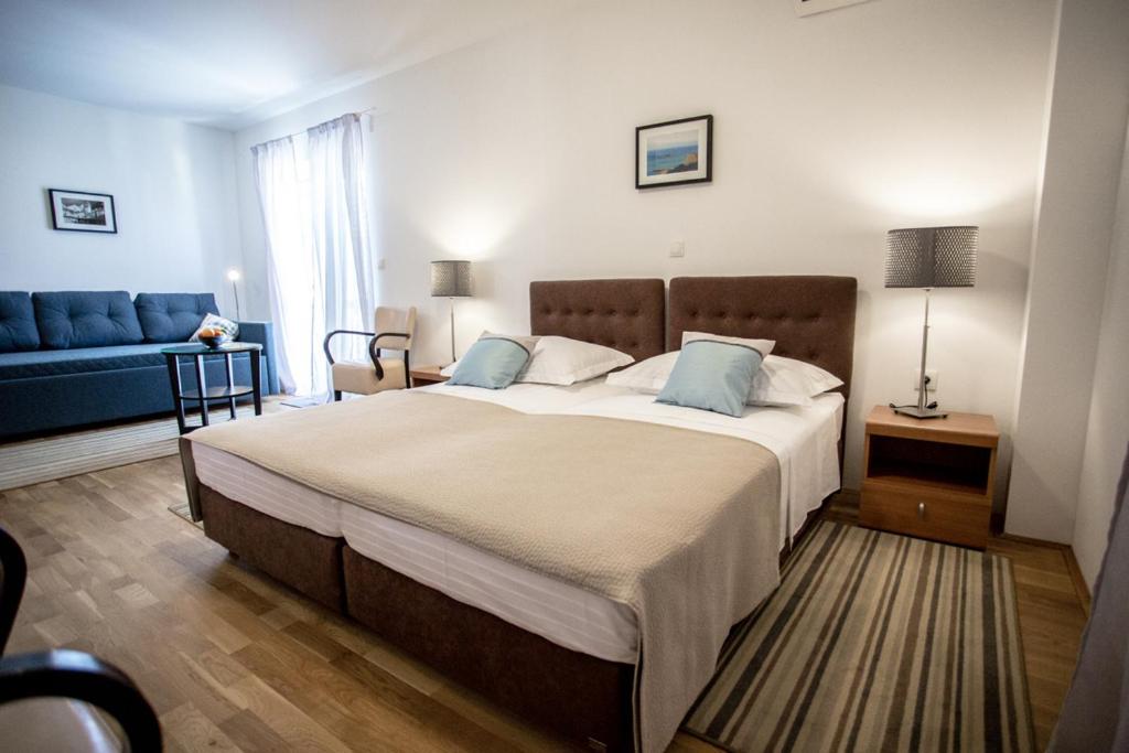 1 dormitorio con 1 cama grande y 1 sofá azul en Rooms Margarita, en Split