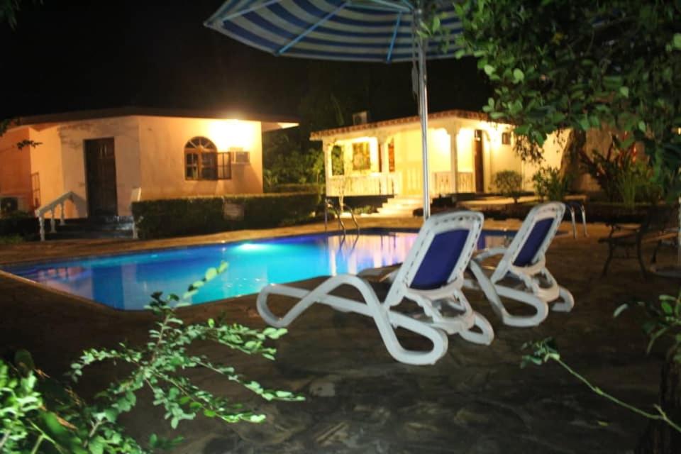 two chairs and an umbrella next to a pool at night at Safina Resort in Zanzibar City