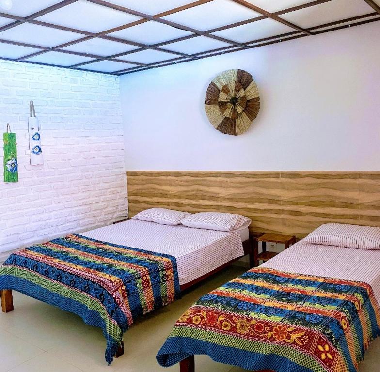 1 dormitorio con 2 camas y reloj en la pared en Pousada das Gaivotas en Guaibim